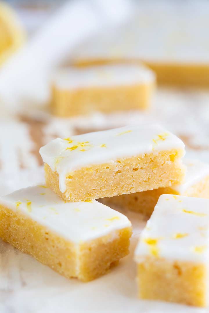 yellow lemon bars with white icing stacked together