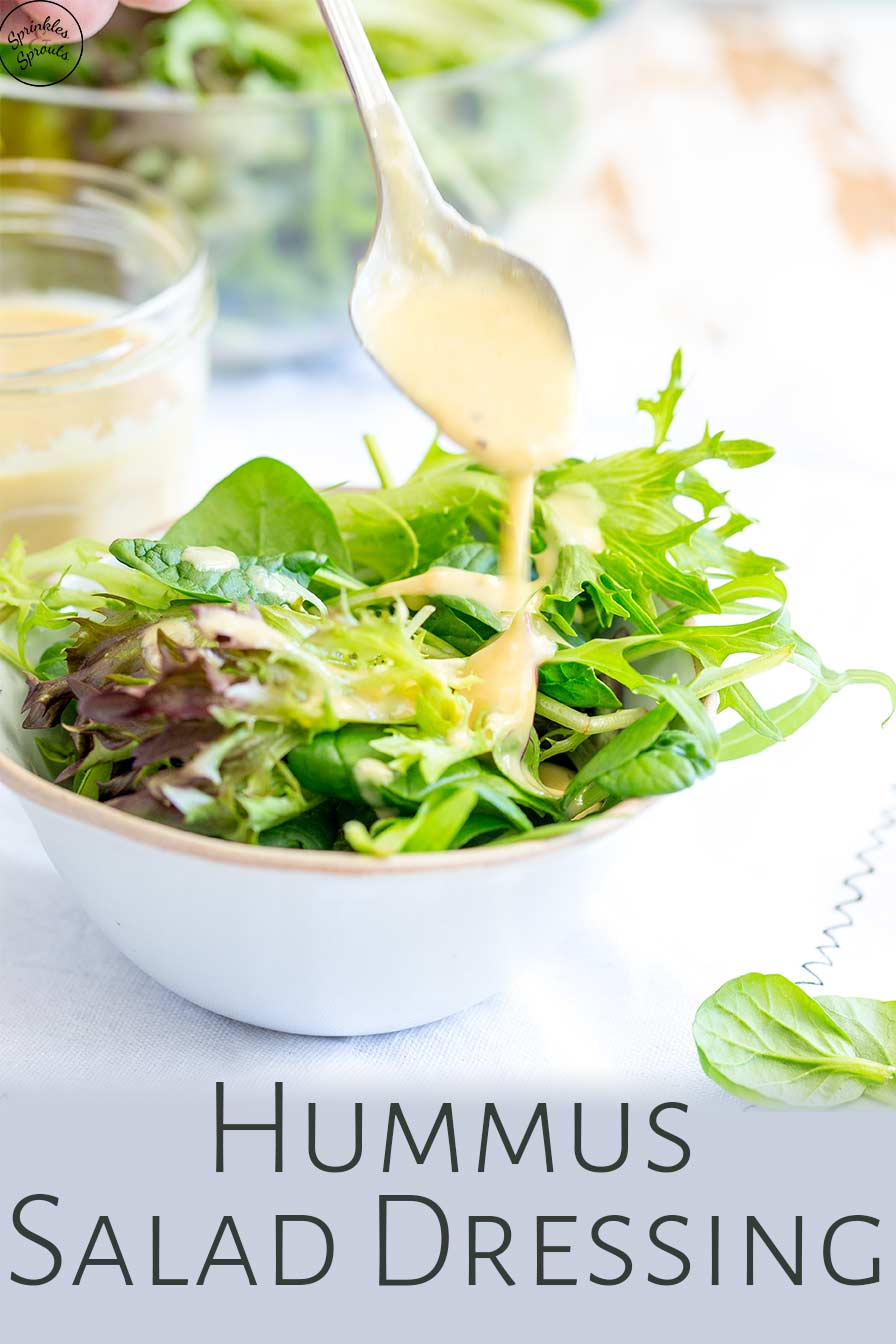 hummus dressing being drizzled over salad with text the bottom