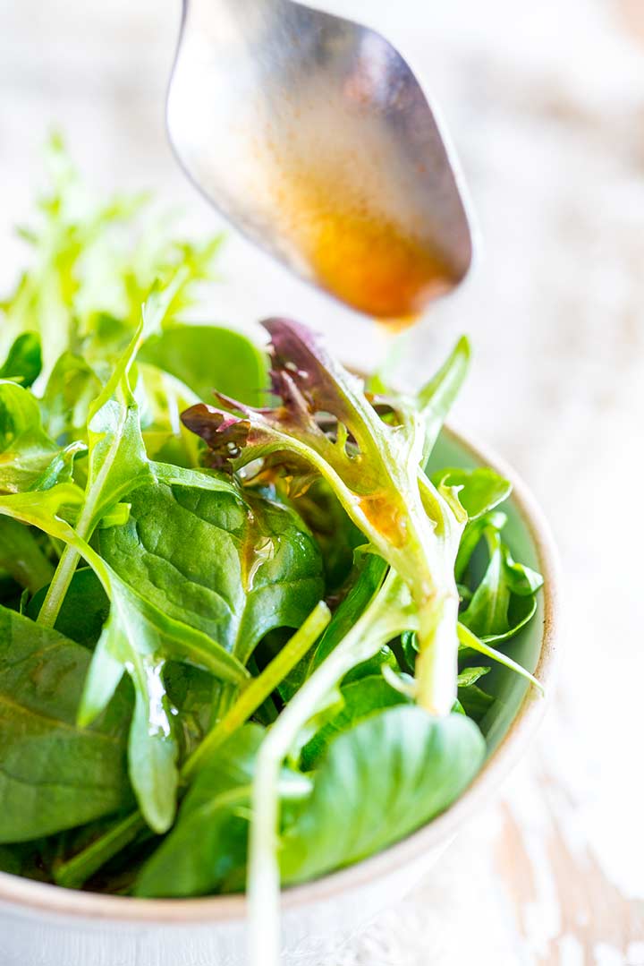 close up on a salad leaf with sriracha salad dressing on it