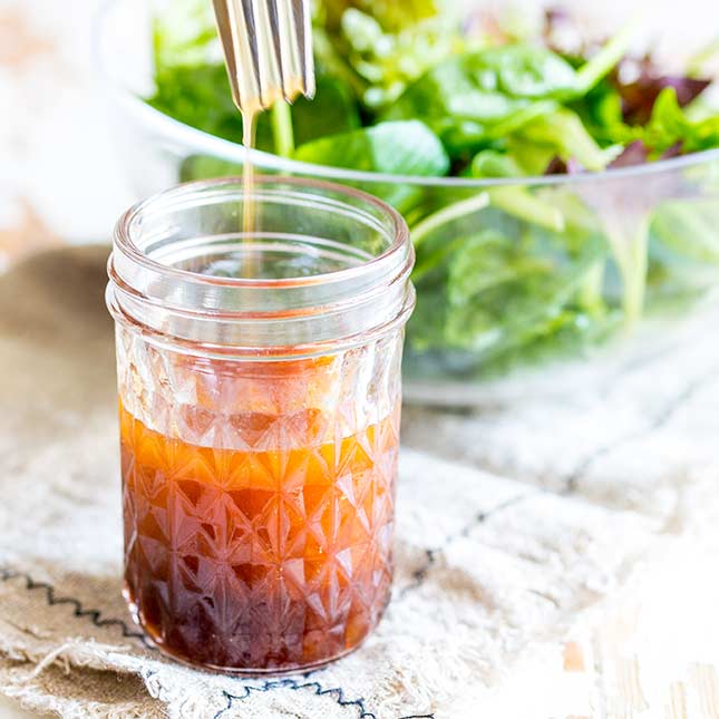close up on a jar of sriracha salad dressing with a fork lifting out of it