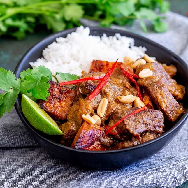close up on a black bowl of Thai beef curry and rice