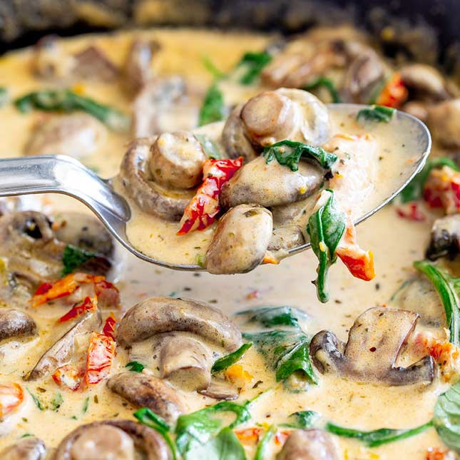 close up on a spoonful of creamy mushrooms with spinach
