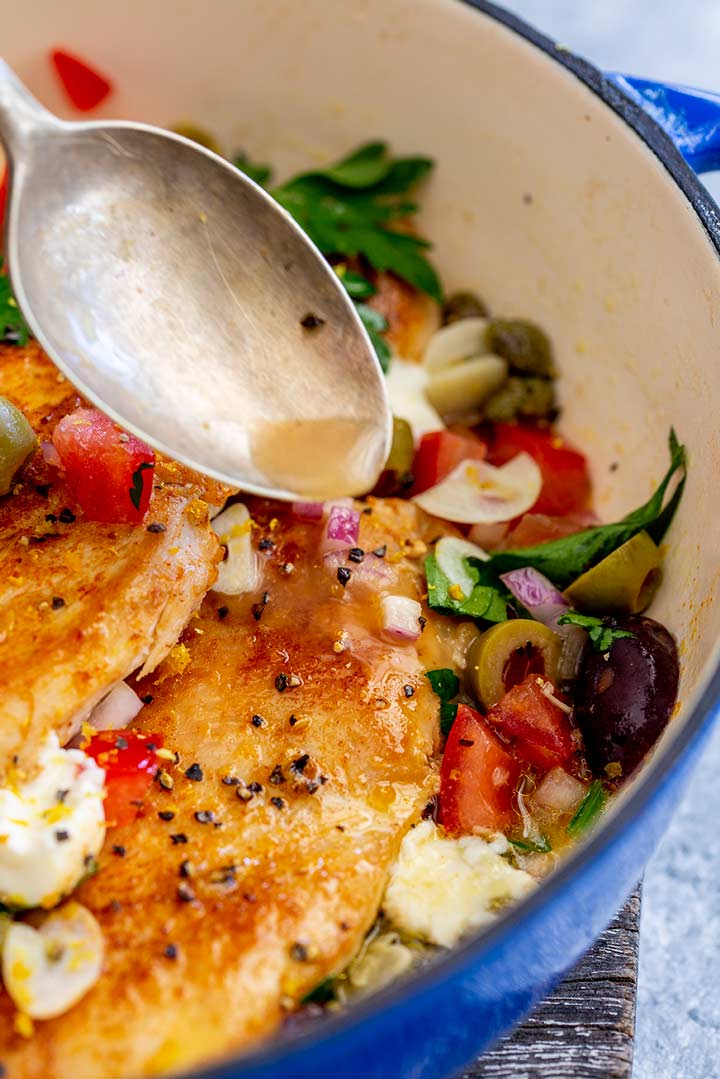 an old spoon drizzling pan juices over the Italian chicken breasts