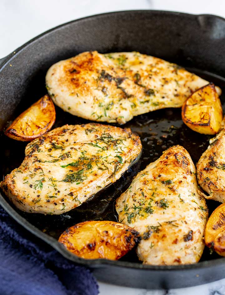 4 chicken fillets in a cast iron skillet with charred lemon