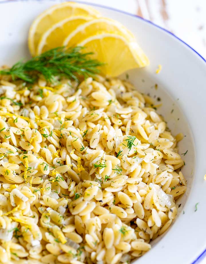 orzo in a white bowl garnished with lemon and dill