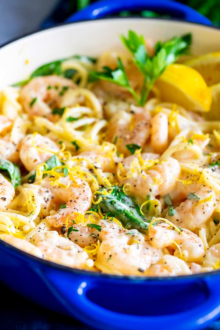 creamy shrimp and pasta in a blue pan garnished with lemon zest
