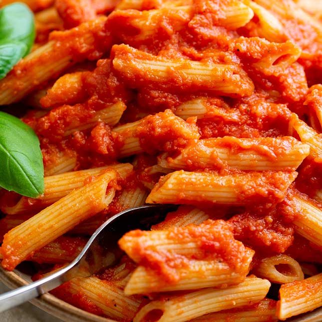 close up on a fork digging into tomato pasta