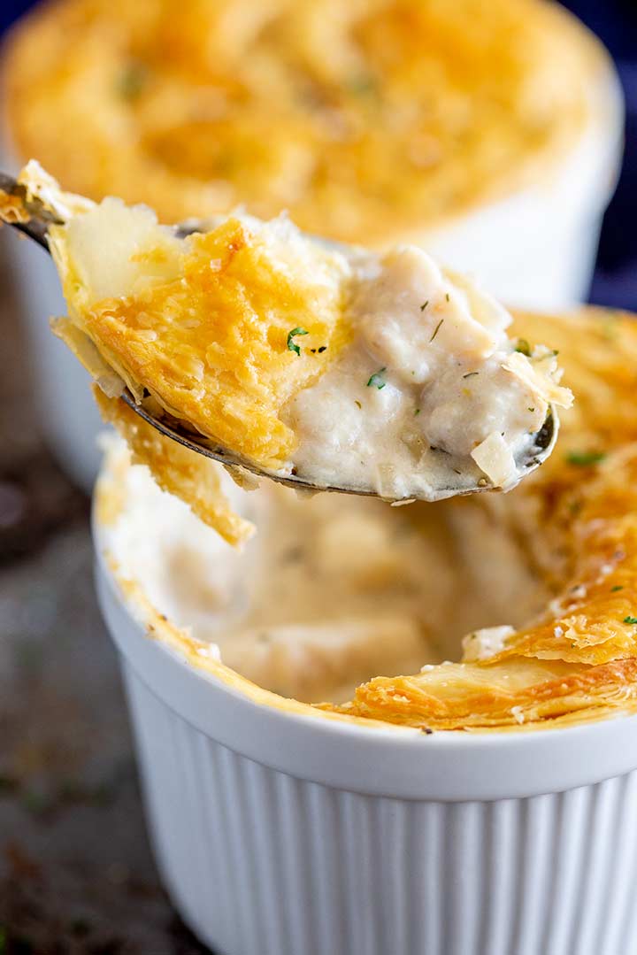 A spoon scooping up creamy fish pie filling and pastry