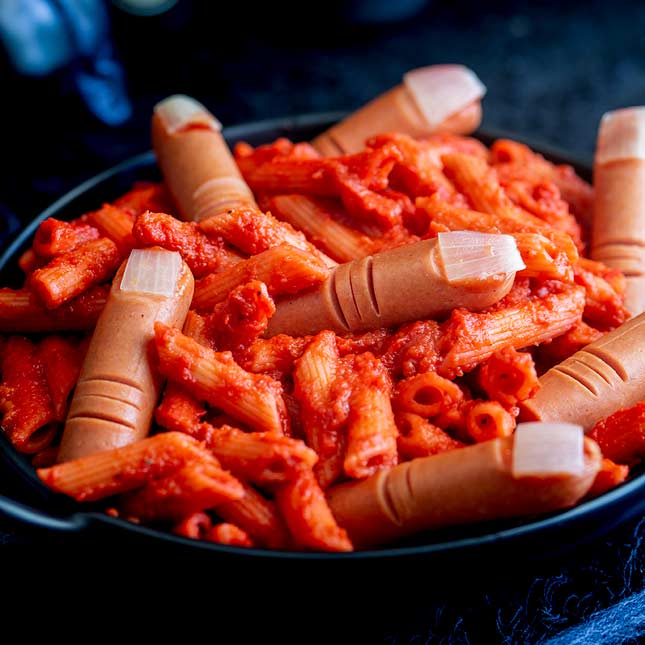 a black bowl willed with red penne and frankfurter fingers