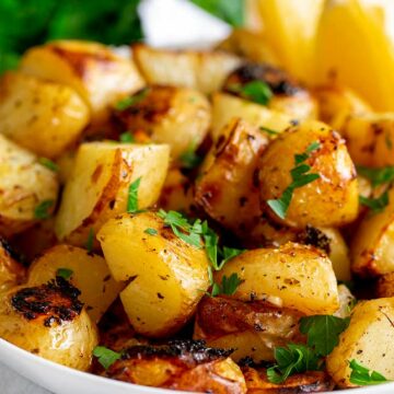 Close up on roasted lemon potatoes in a white bowl