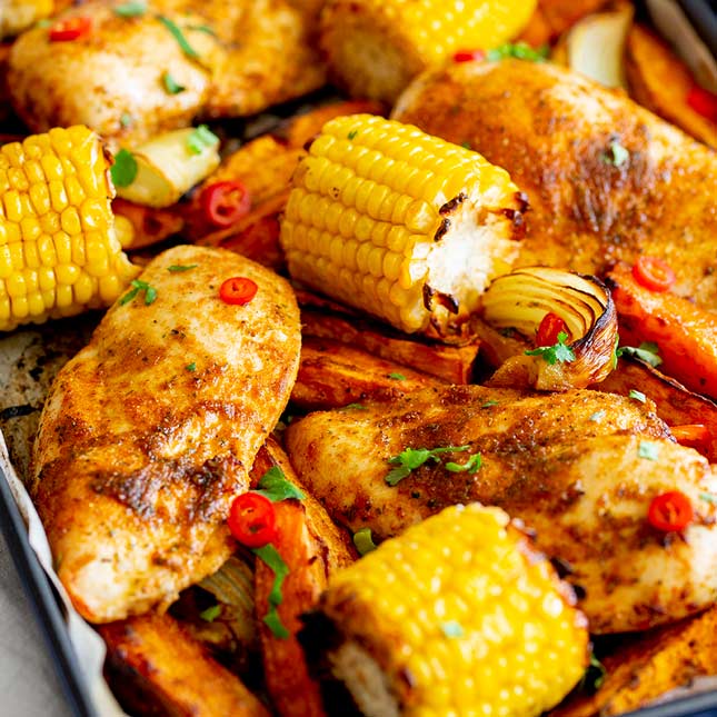 square picture of a peri peri chicken tray bake with vegetables and cili