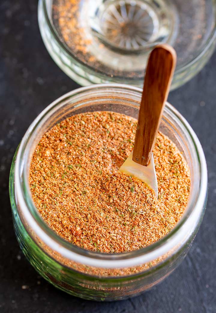 overhead shot of a glass jar filled with a seasoning blend, with a wooden and shell spoon in it