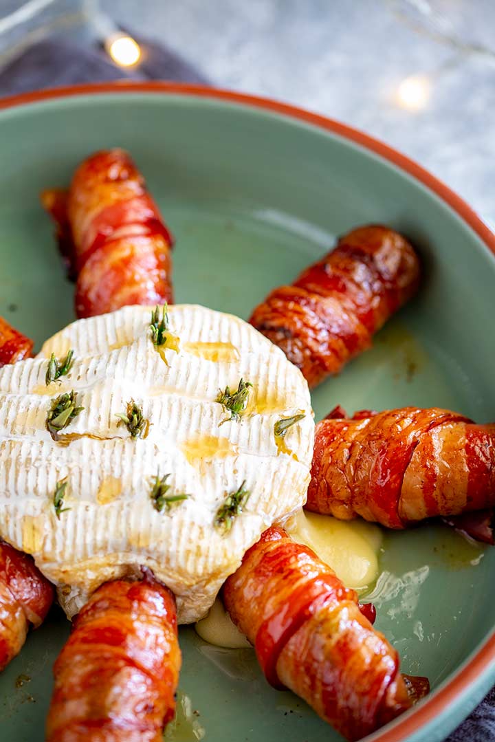 a round of brie with bacon wrapped sausages around it
