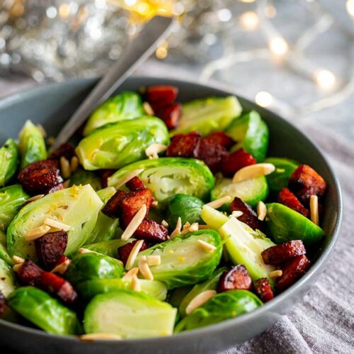 a spoon in a grey bowl of Brussel Sprouts with chorizo and almonds