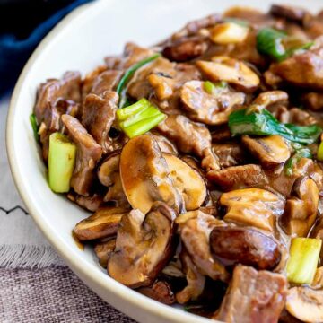 sliced mushrooms and beef in a white bowl with a brown sauce
