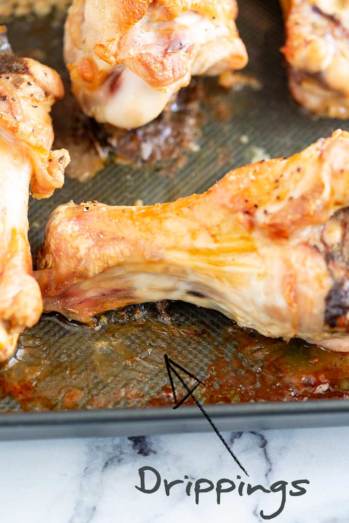 close up on the turkey drippings on a tray of roasted wings