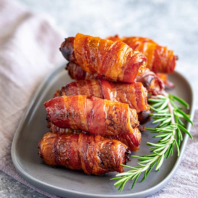 close up on crispy bacon wrapped around sausages