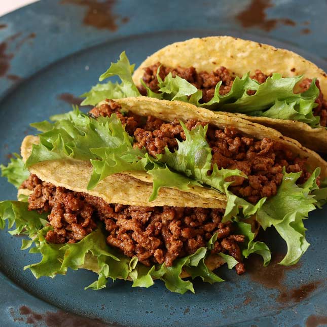 close up on 3 hard beef tacos on a blue plate