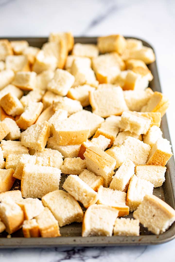a sheet pan with cubes of bread on it on a marble table