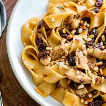 super close up on thick pasta noodles with chicken, raisins and pine nuts