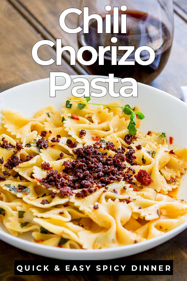 wooden table with a bowl of chorizo pasta with text at the top and bottom