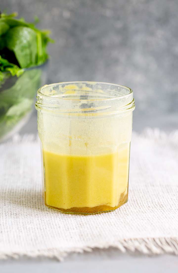 mixed up salad dressing in a glass jar on a white mat