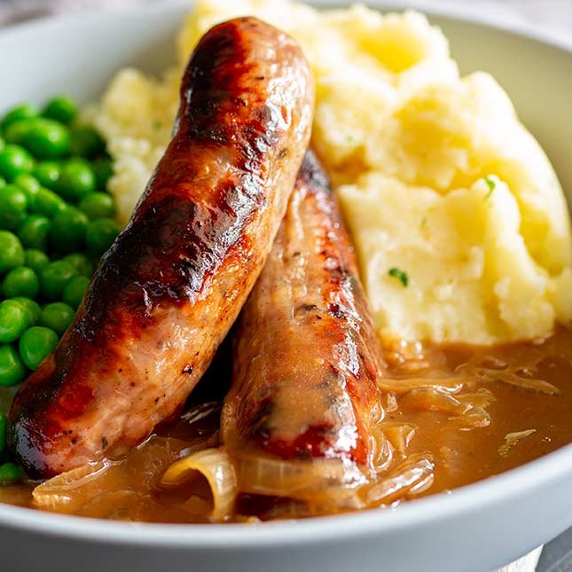 close up on two sausages in gravy