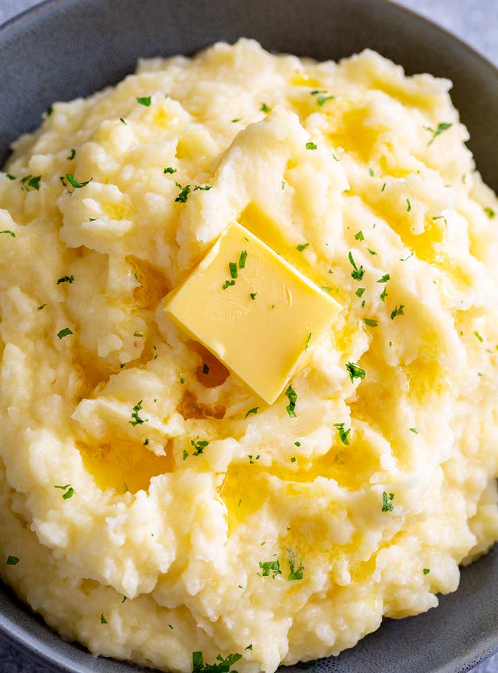 overhead of a grey bowl of mash with a pat of butter on top