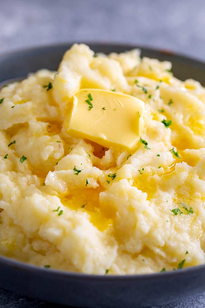 mashed potatoes in a grey bowl with butter on top