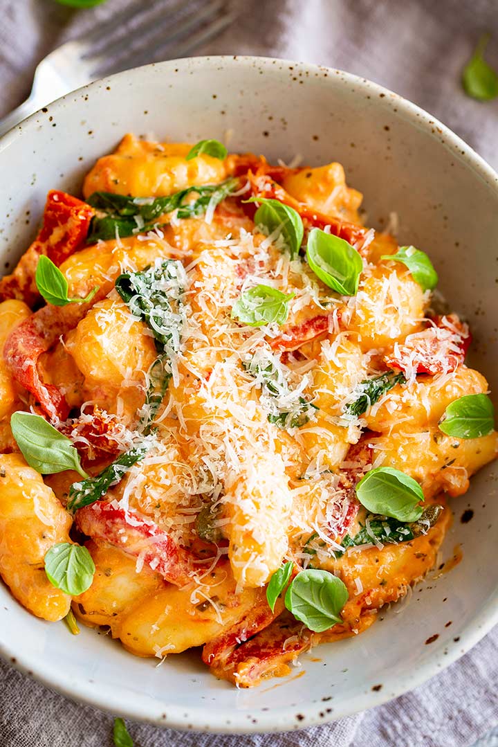 overhead shot of a bowl of gnocchi sprinkled with parmesan and basil