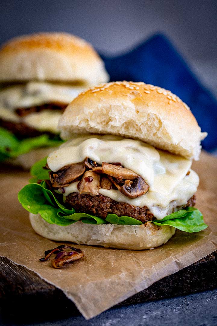 two mushroom Swiss burgers on brown paper on a wooden board