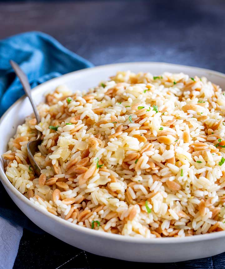 a bowl of pilaf sat on a dark table with a blue napkin