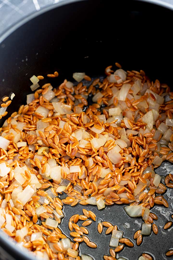 toasted orzo and onion cooking in a pan
