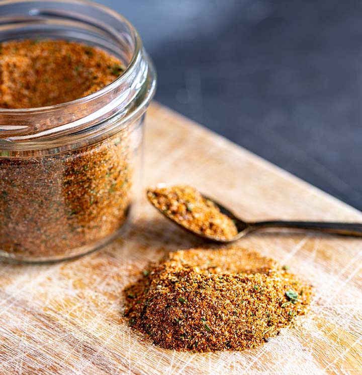 spice blend on a wooden board with a jar and spoon in the background