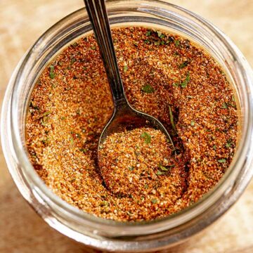 close up on a spoon in a round jar of spice blend