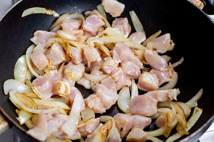 chicken and onions cooking in a wok