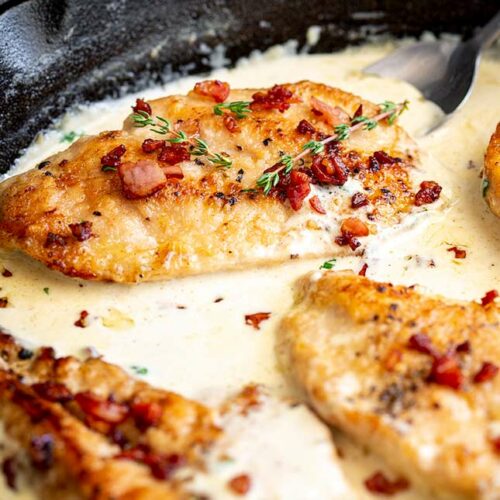 close up on a cooked chicken breast with bacon and cream sauce
