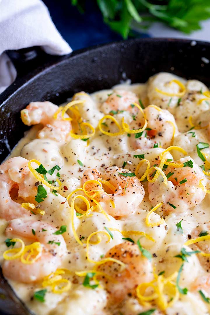a skillet filled with creamy gnocchi and shrimp with lemon zest and pepper