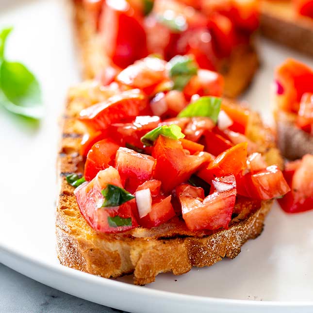close up on the chopped tomatoes on top of crust bruschetta