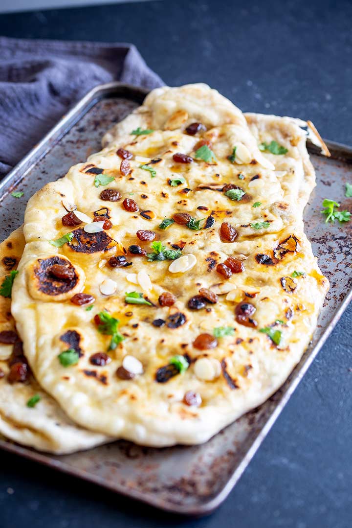 peshwari naan garnished with cilantro, sultanas and almonds on a melt tray