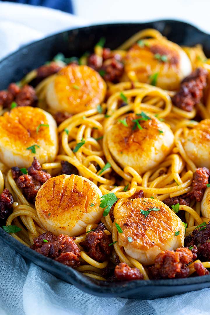 paprika stained seared scallops on a a bed of pasta