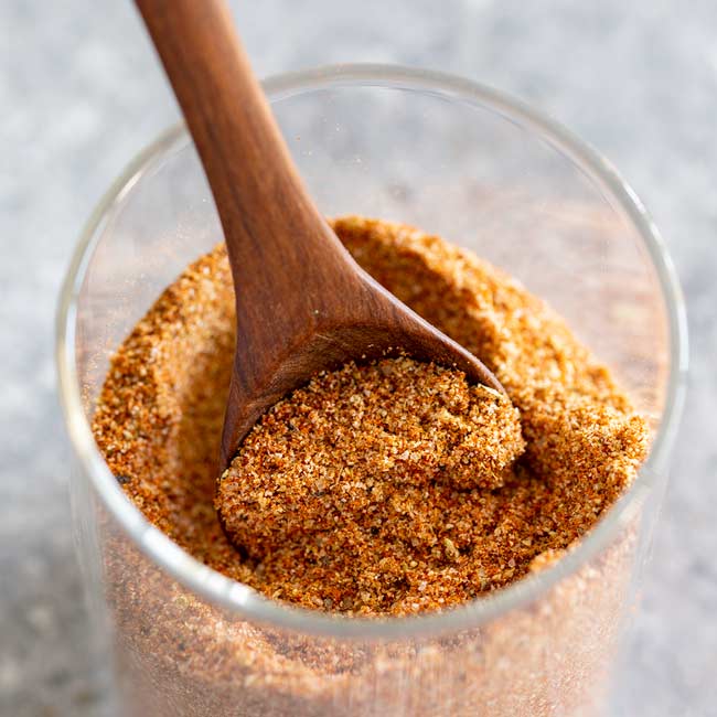 Close up square picture of taco seasoning on a wooden spoon