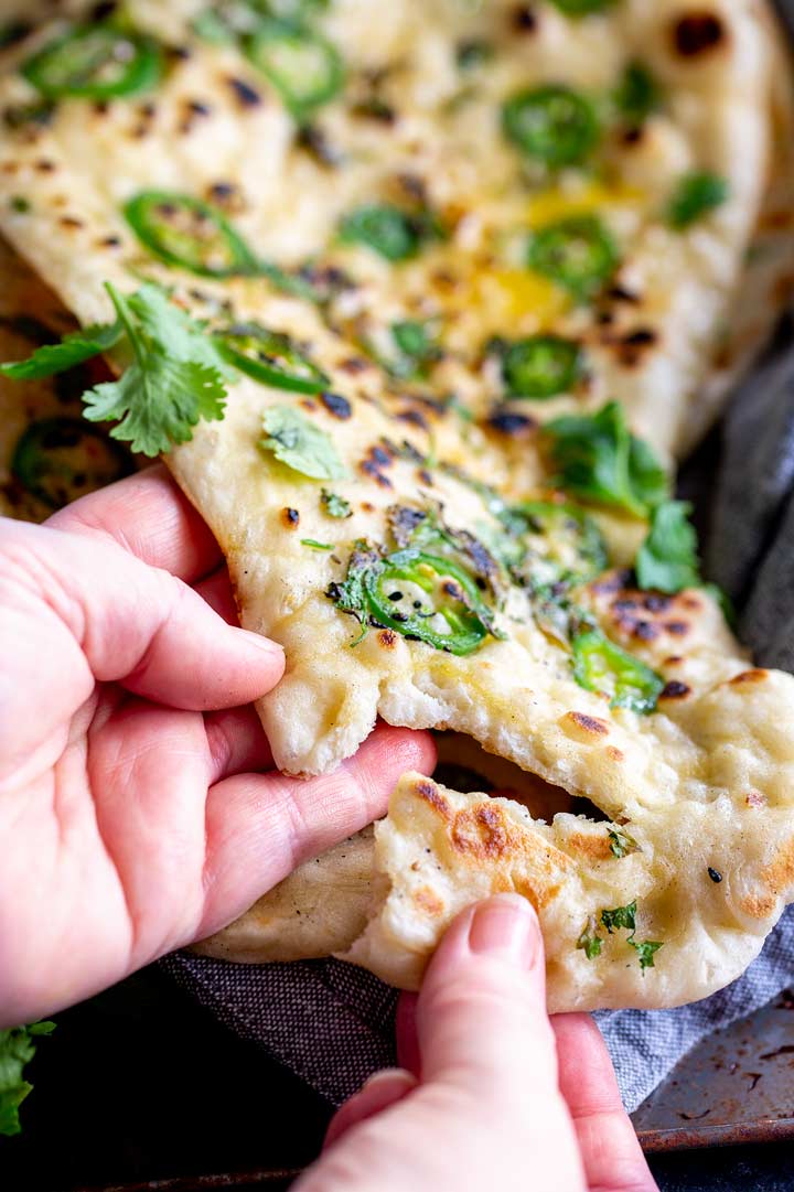 a naan bread being pulled apart with two hands