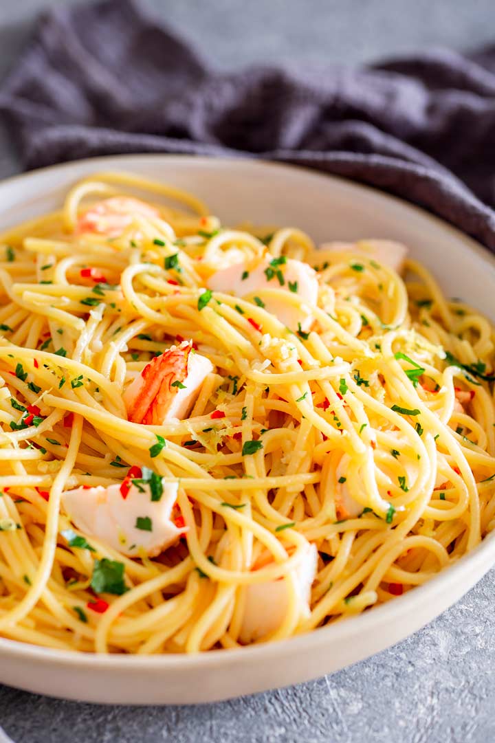 lobster spaghetti with parsley and chili on a grey stone table