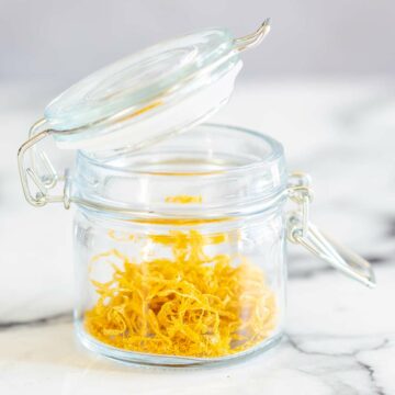 close up of a clip top jar with dried lemon peel in it, on a marble table