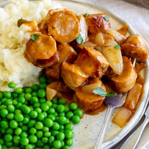 chunks of sausages in gravy with peas and mash