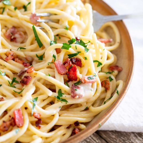 close up on creamy bacon sauce on a bed of spaghetti