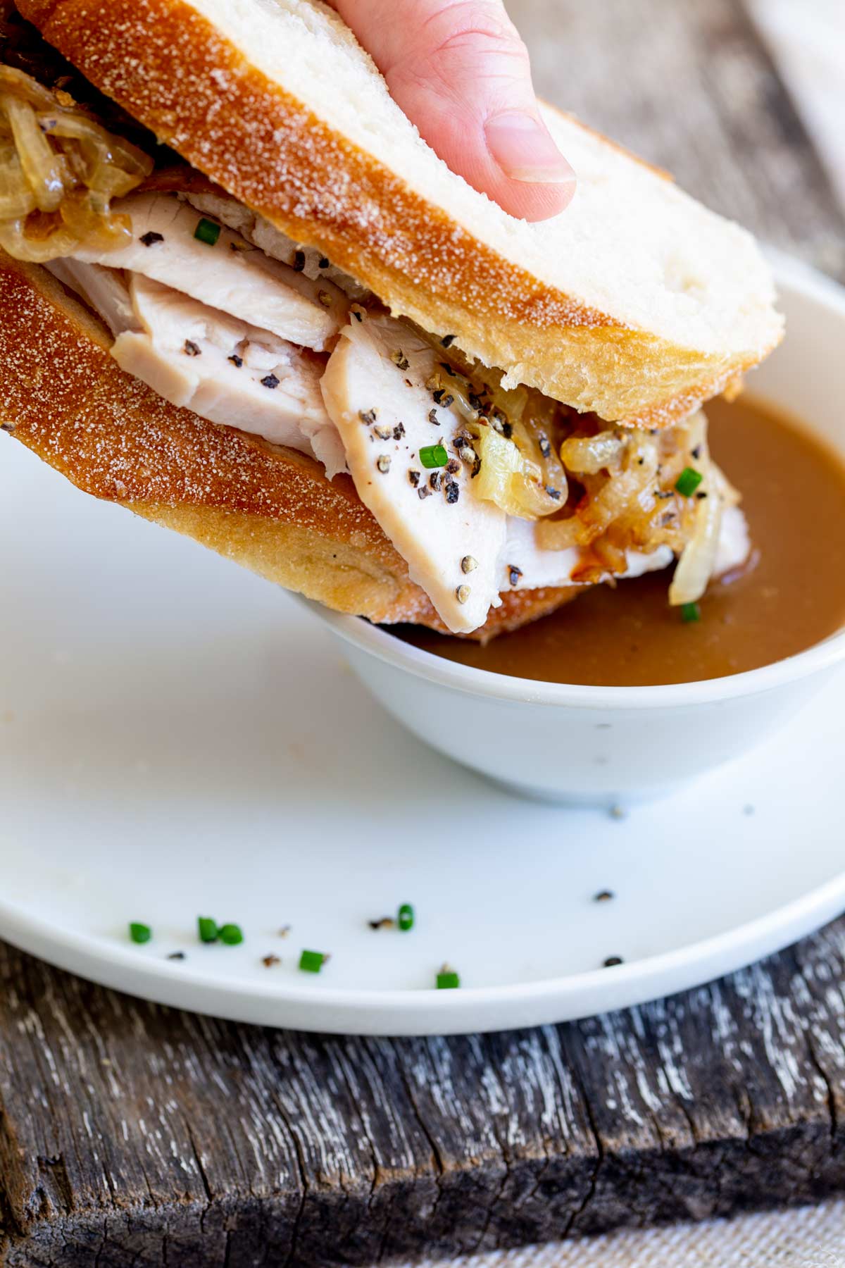 a turkey sandwich being dipped into gravy