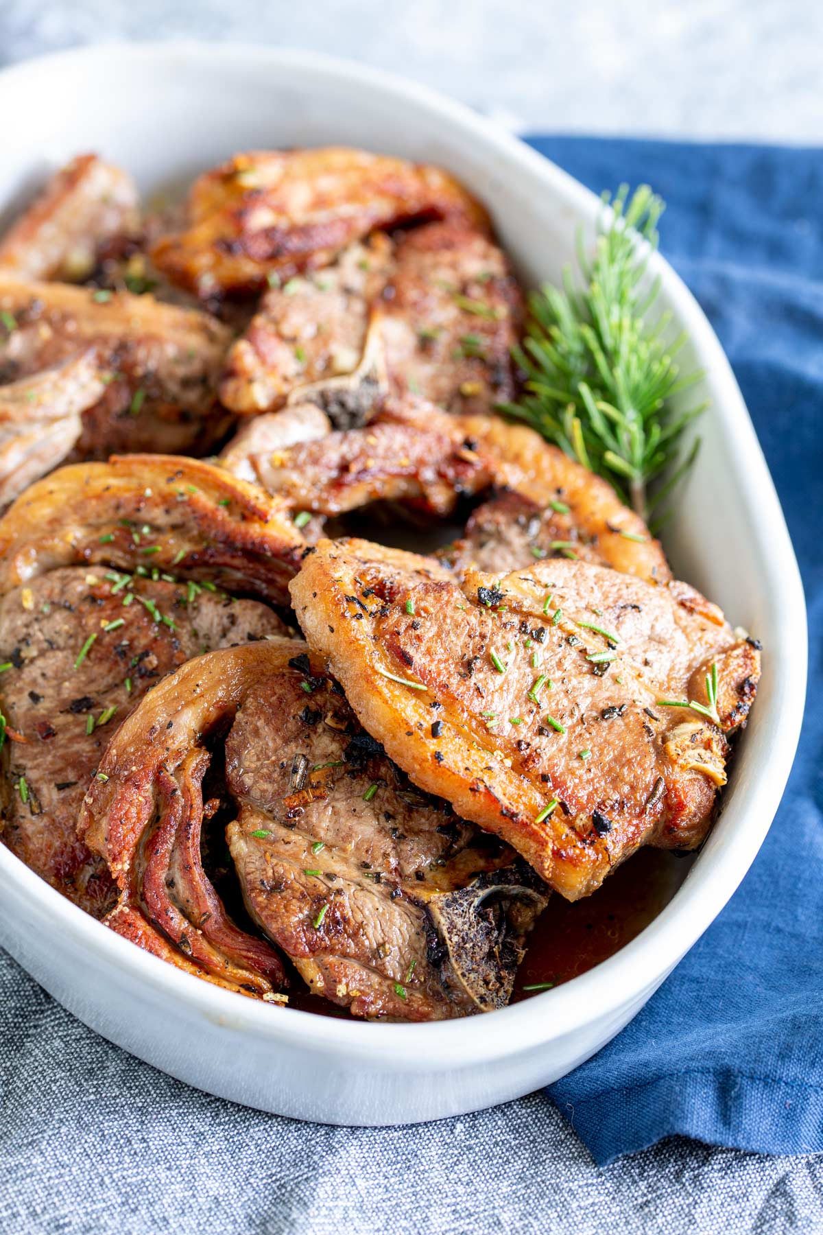 lamb porterhouse in a white serving dish with rosemary sprigs