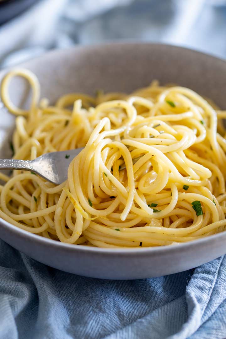 a fork swirling lemon spaghetti out of a grey bowl